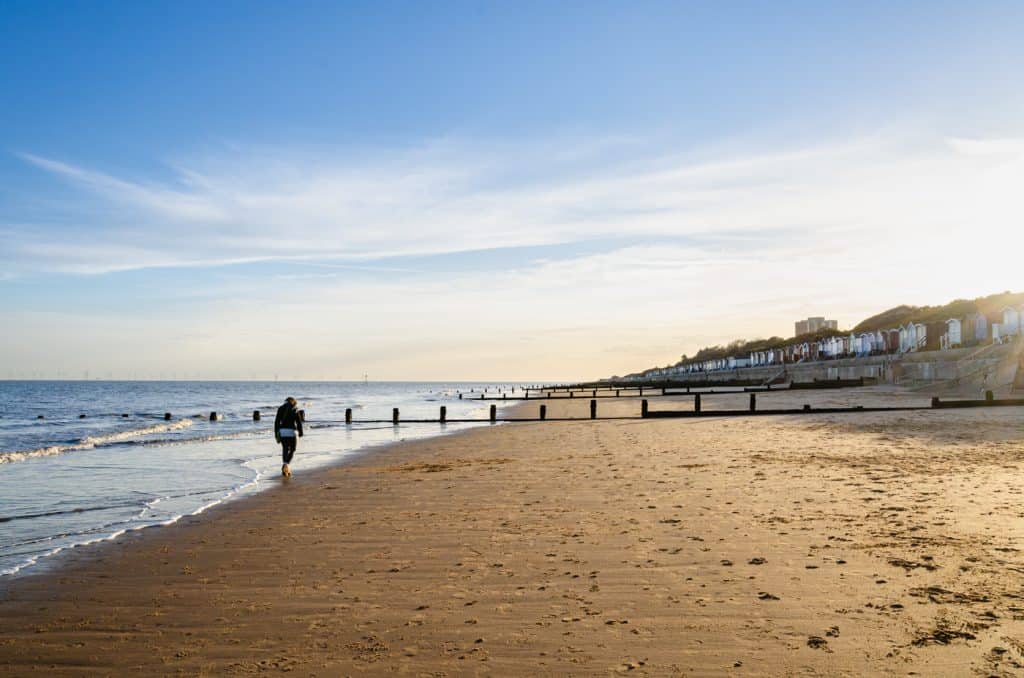 A women walking at the beach in Suffolk.