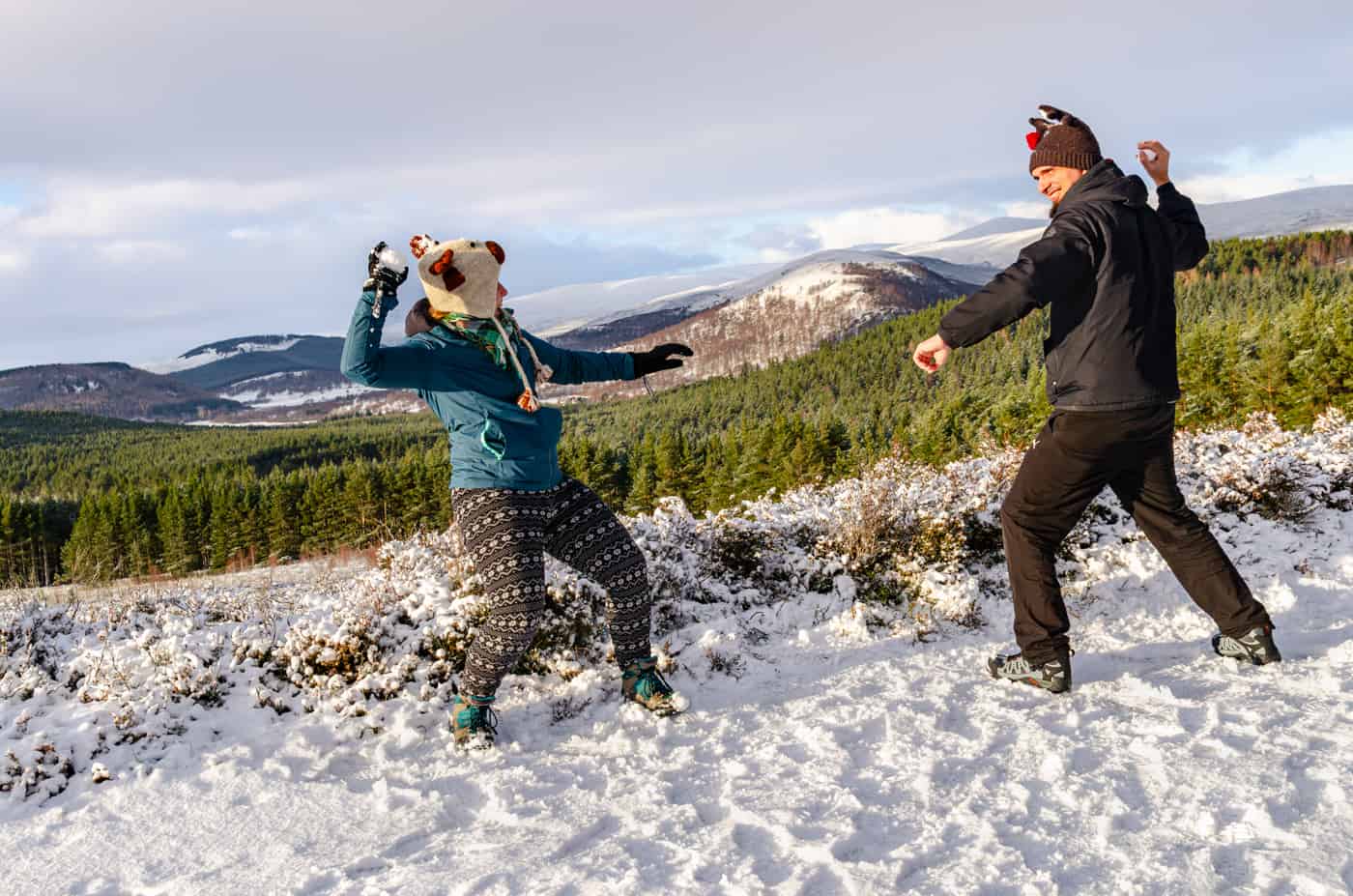 A couple having snowball fight on a sunny winter day in Scotland.