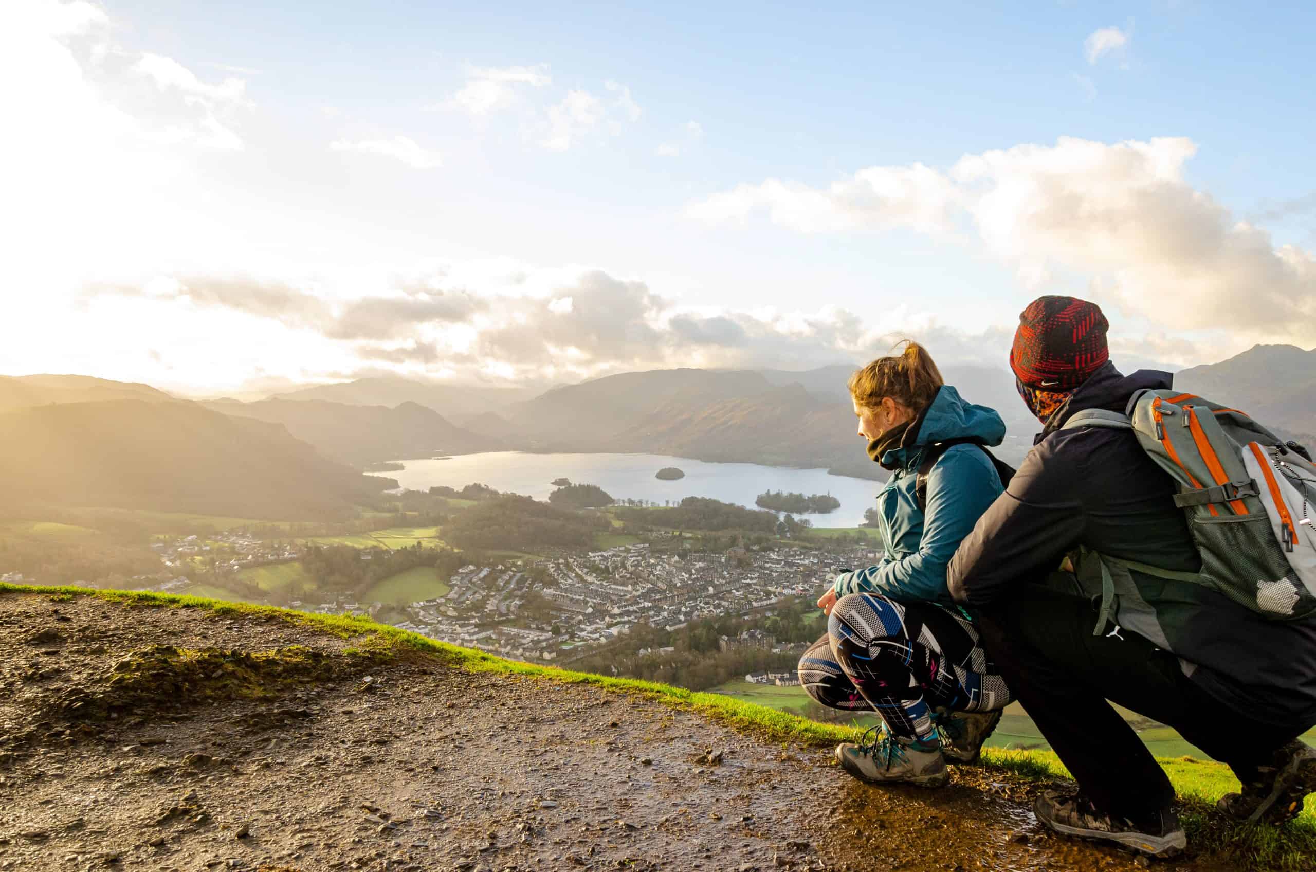 A couple looking at the town of Keswick from a viewpoint.