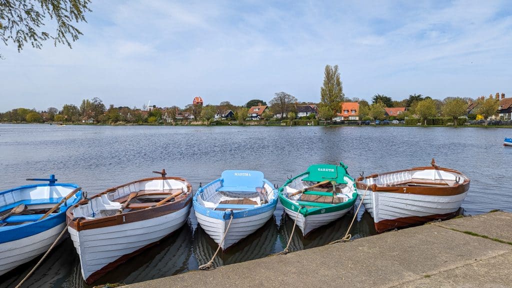 Boats on the lake in Thorpeness in Suffolk Coast and Heaths AONB, with the House of Clouds in distance.