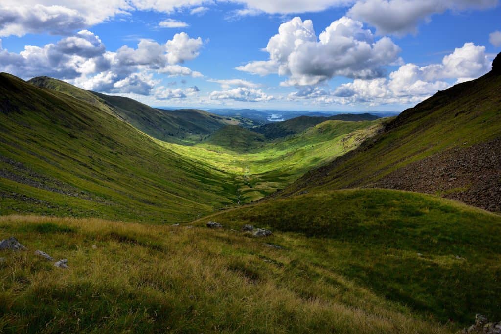 View at a green valley with hills clouds on a sunny day.