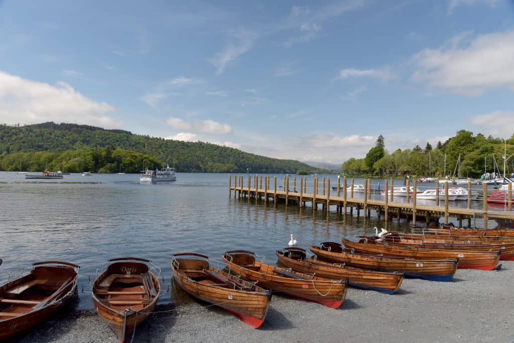 Wooded boats and a pier with a lake and hills at back.