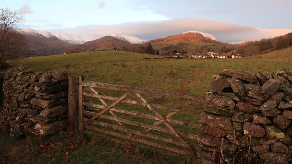 View at a wooden and stone gate with snowy peaks at back.