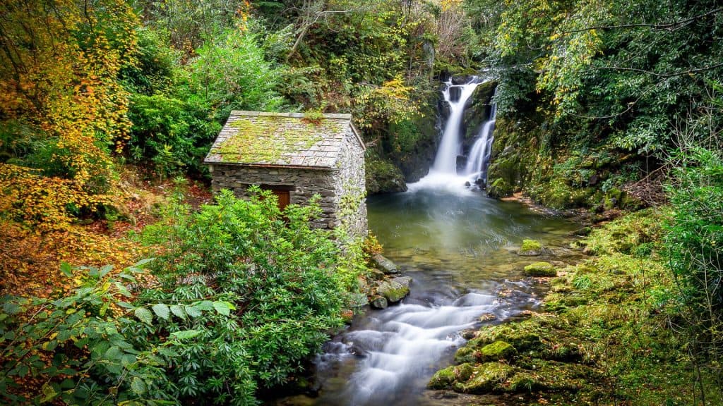 A waterfall in Lake District with a little house.