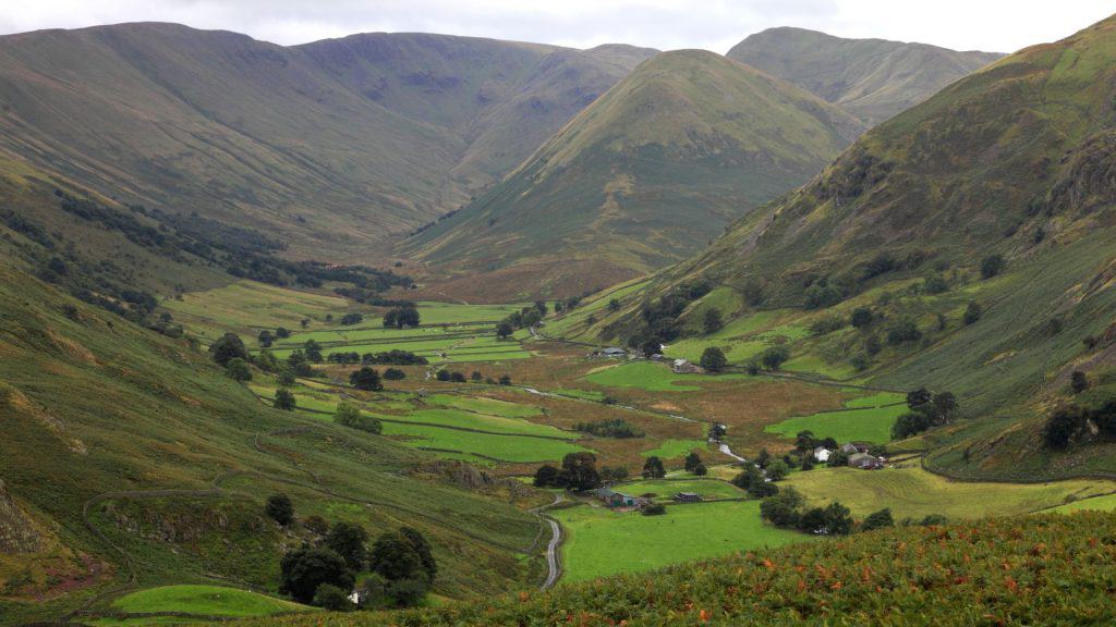 View of a green valley with hills on sides in the Lake District.