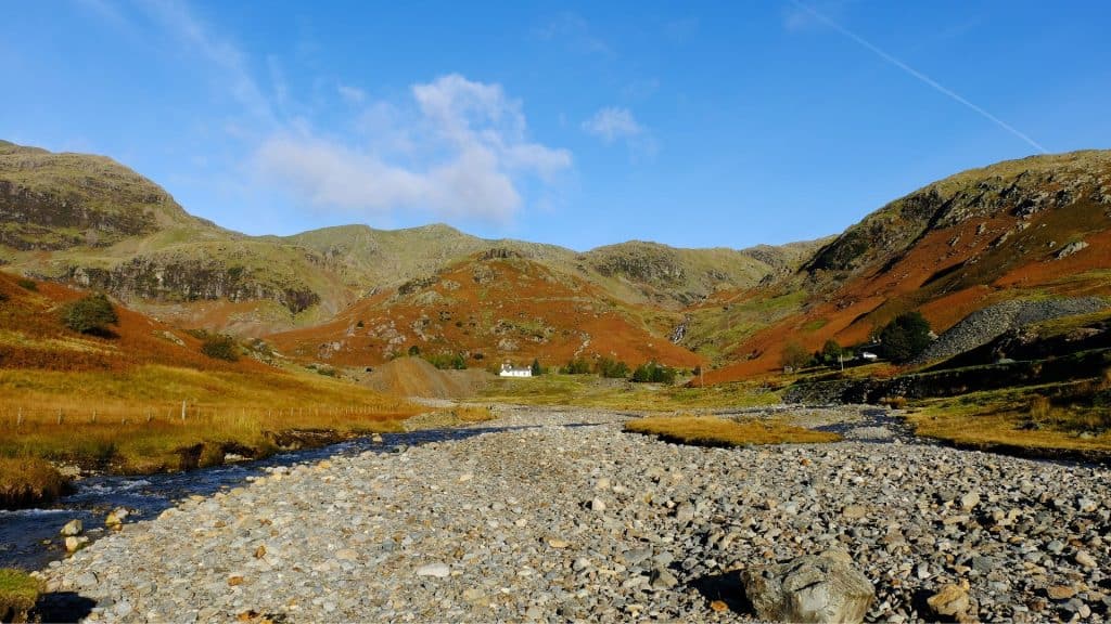 View at a river, old white cottage and hills.