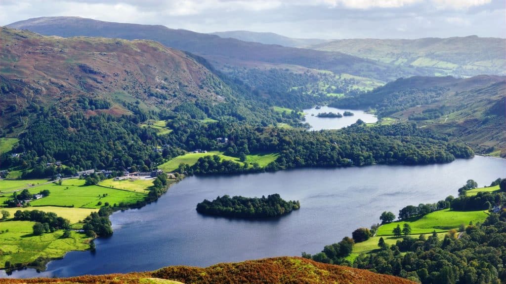 Views at a lake with hills and forest in the Lake District.