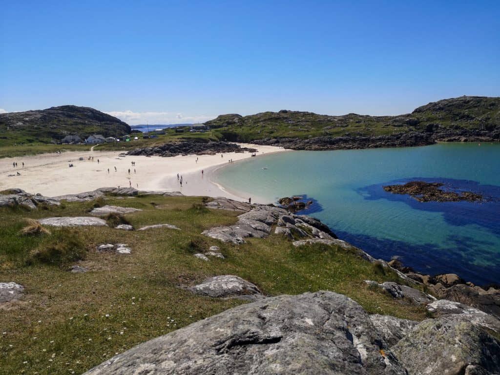 Achmelvich beach in Scotland on a sunny day with a few people on the beach, one of the must places to visit in Scotland.