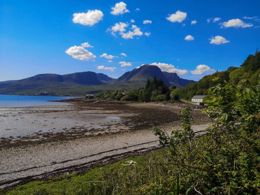 View at a beach, cottage and mountains on the NC500 route on a summer sunny day.