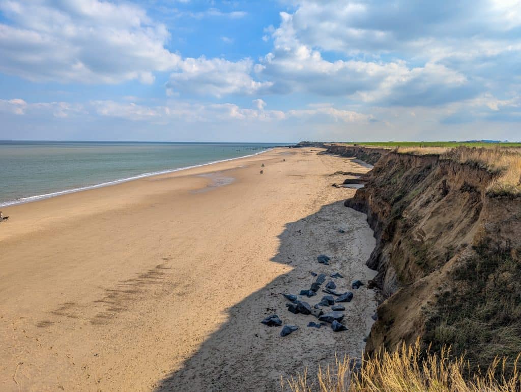 View at the cliffs and a long sandy Happisburgh beach on a sunny day.