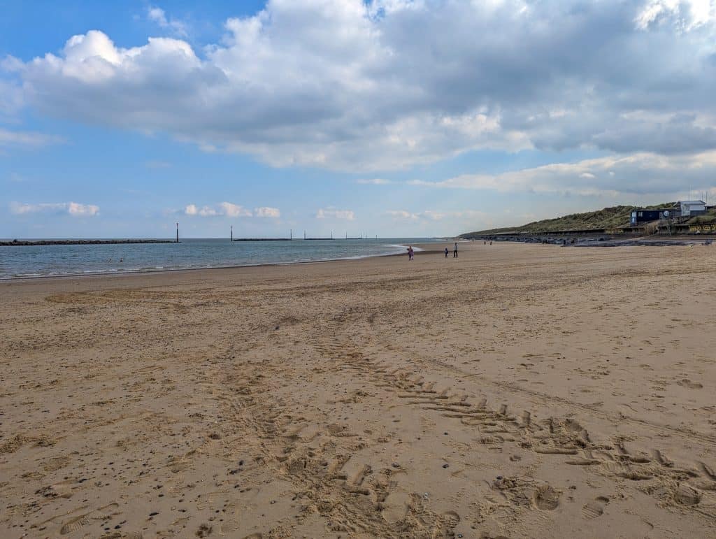 Sea Palling beach with sea and people walking on the beach.