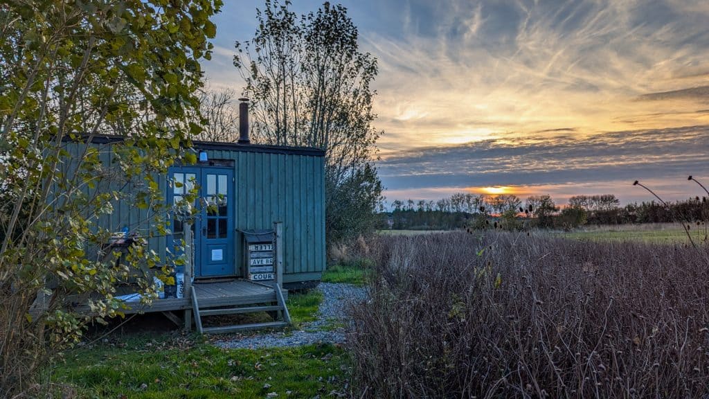 A small shepherd hut with trees during sunset in autumn.