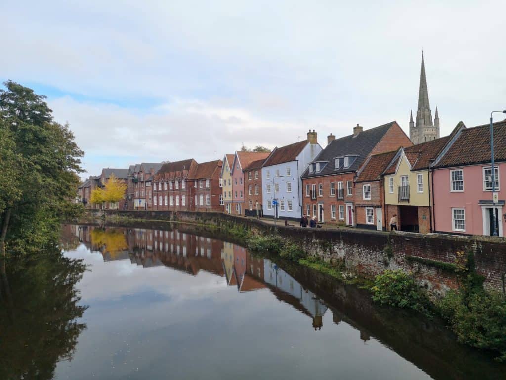 A view at the river Wensum and houses with the Cathedral at back - Norwich Riverside Walk.