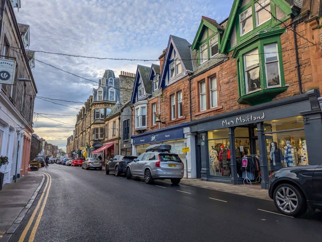 A high street with shops and cars in North Berwick in Scotland.