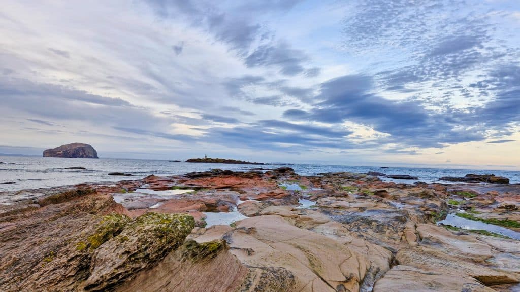 Sunset at the Seacliff beach in Scotland with a lighthouse and Bass Rock at the distance. A perfect day trip from Edinburgh.