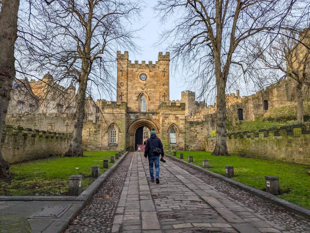 A person walking towards the entrance of the Durham Castle.