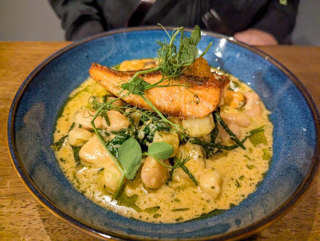 A piece of scottish salmon in a rich sauce.