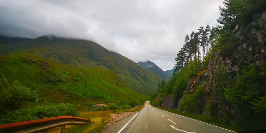 A road to the Isle of Skye with green hills and clouds.