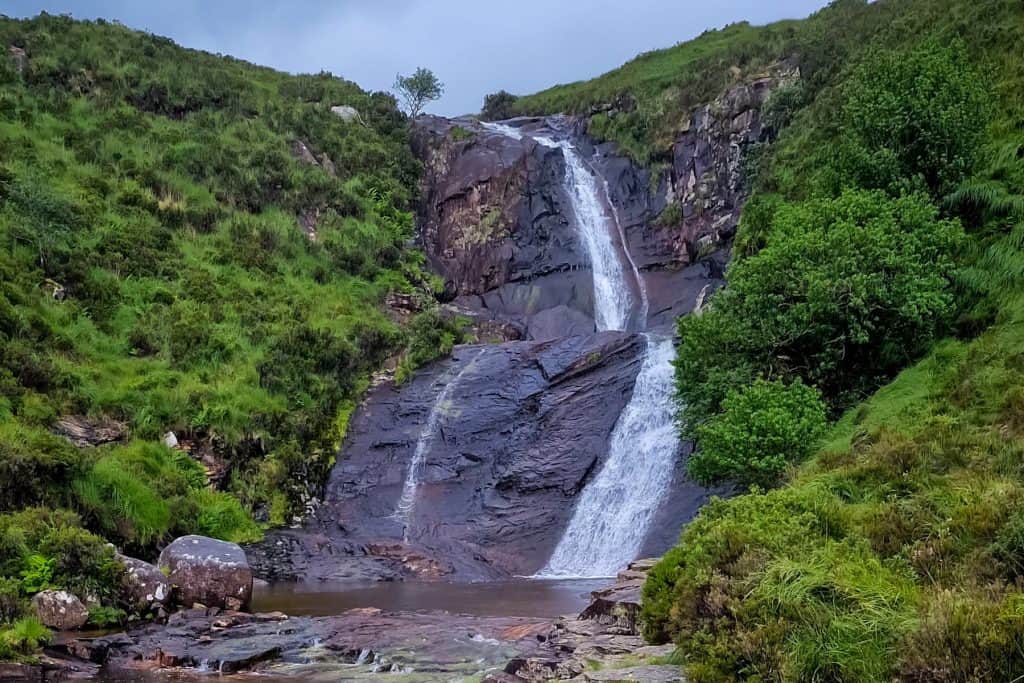 A view at the Eas a' Bhradain Waterfall in summer with green surrounding.