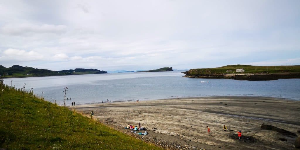 View at the Ann Coran beach with people enjoying beach activities, sea and cottages at back.