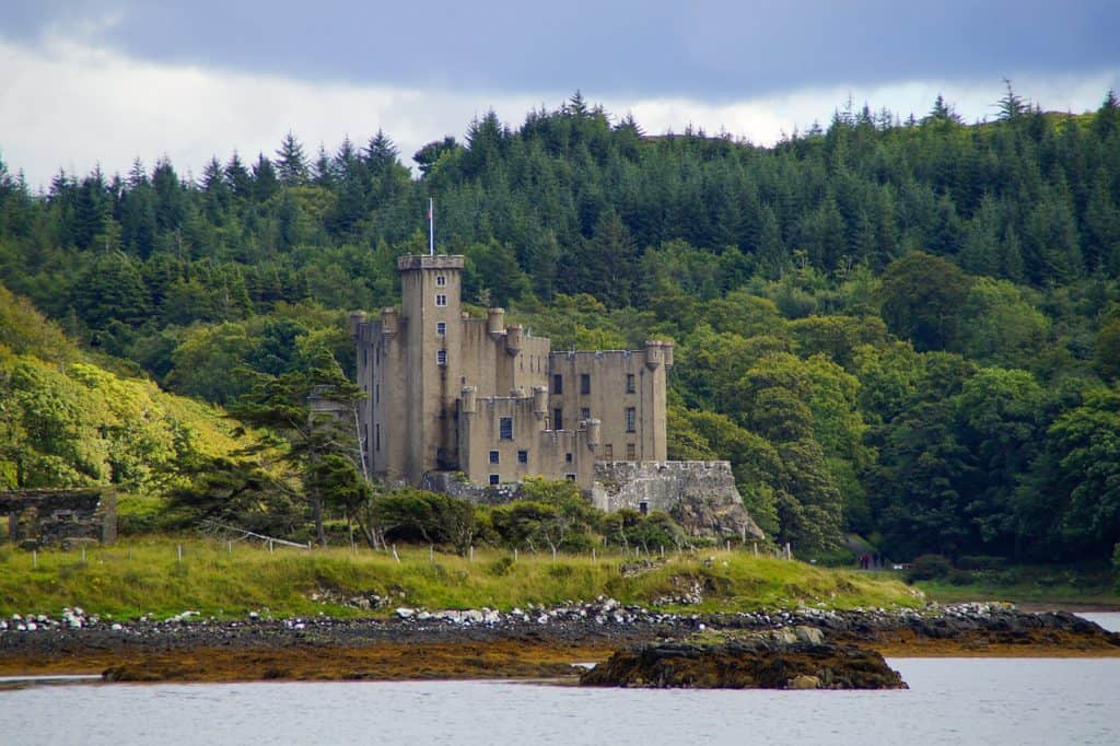 Dunvegan Castle with a lake in front and forest behind the castle.