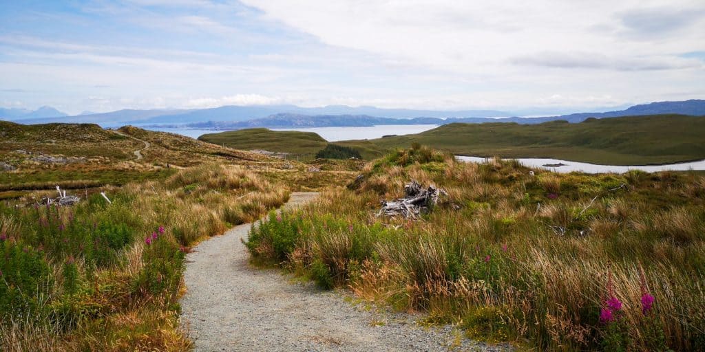 A trail leading from the Old Man of Storr view lakes and mountains views at back.