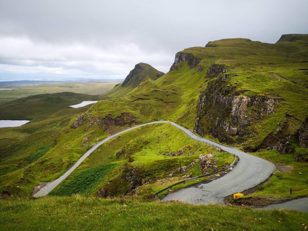 Views of the Quiraing with rock formations covered in greenery and a vining road. Hiking Quiraing is one of the things to do on the Isle of Skye.