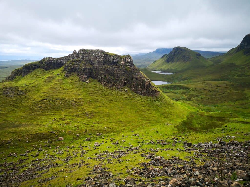 Views from Quiraing on the rock formations covered in greenery and small lakes.
