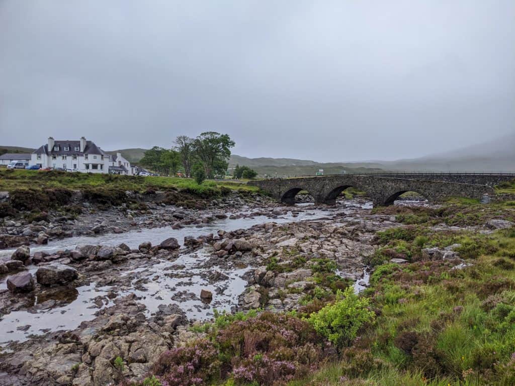 View at the Sligachan bridge, old cottage and river on a foggy summer day.