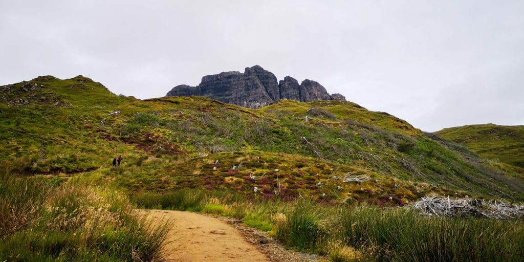 A trail leading to the Old Man of Storr with rock formation at back.