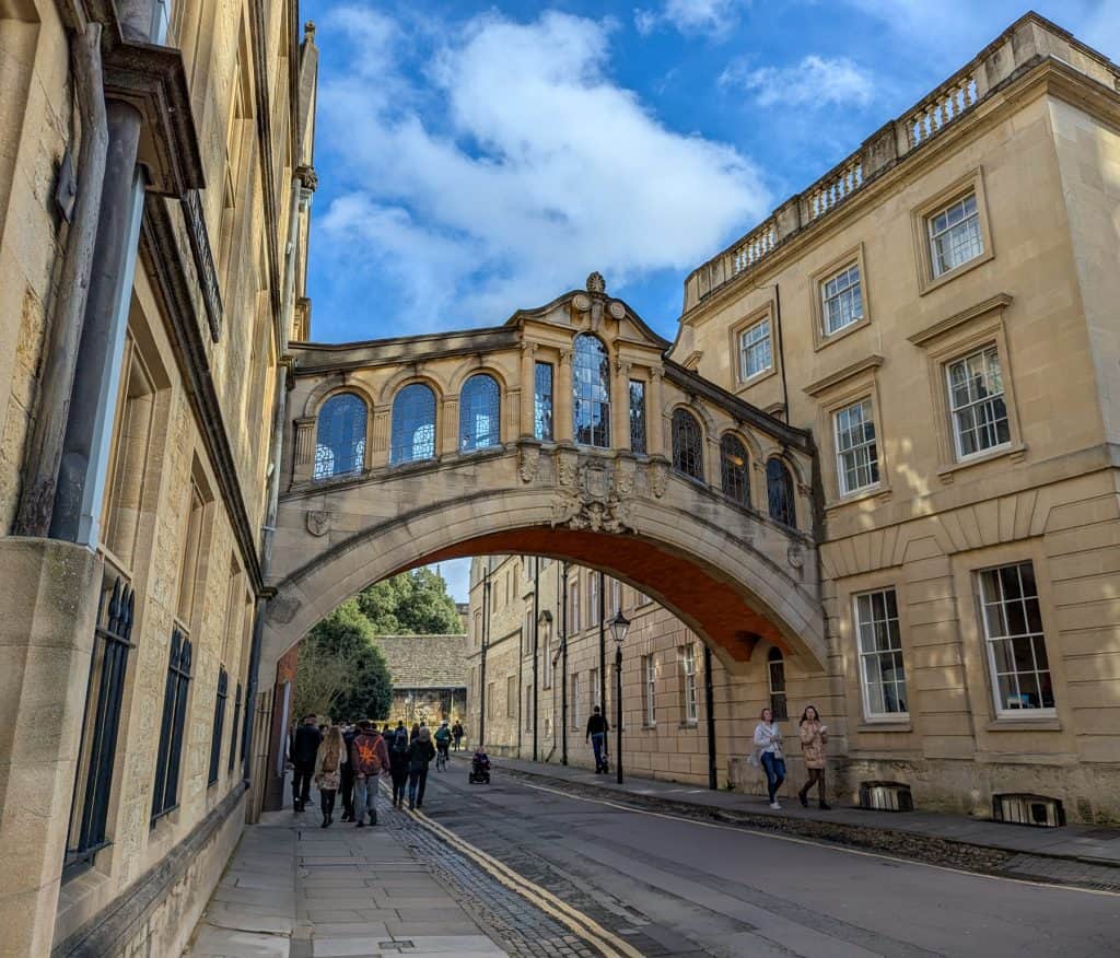 View at the famous Bridge of Sighs in Oxford with many people walking underneath it.
