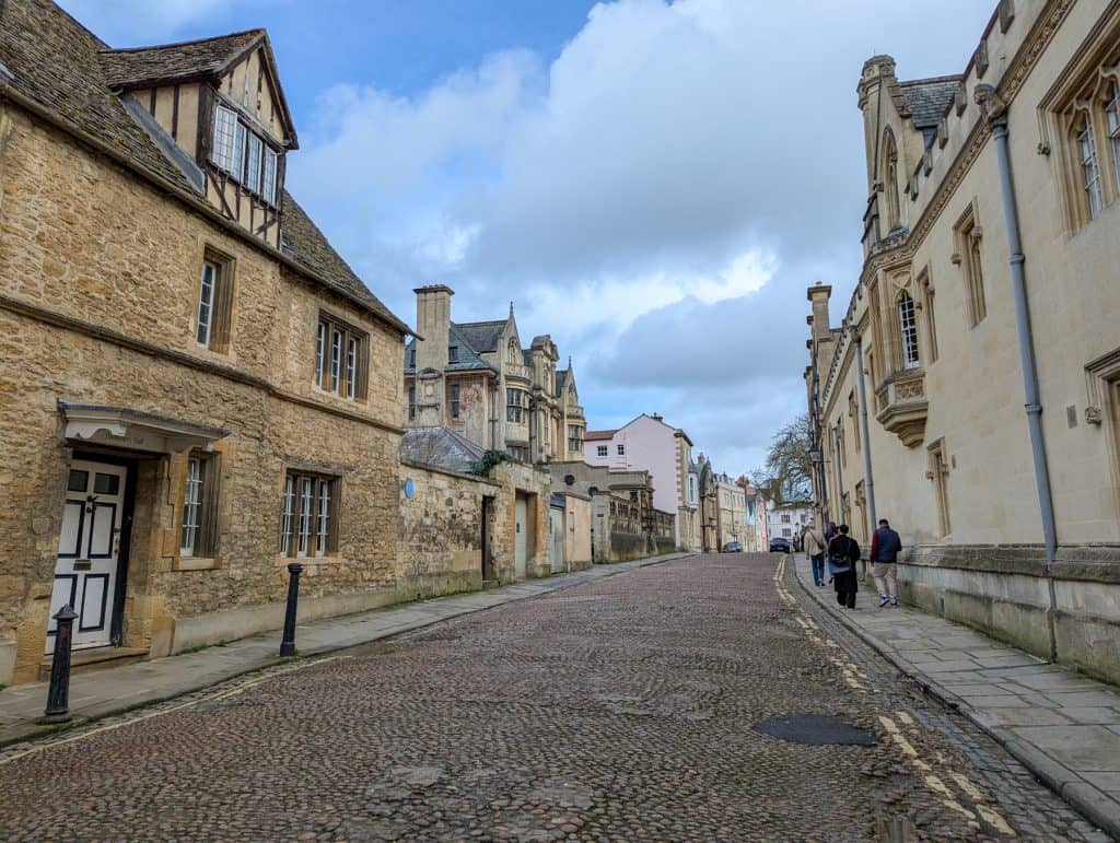 A mediaeval street in Oxford with people walking on pavement.