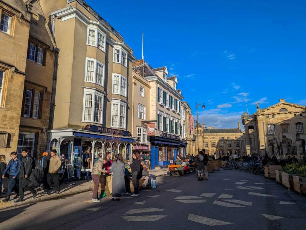 Busy street in Oxford with people on a sunny day.