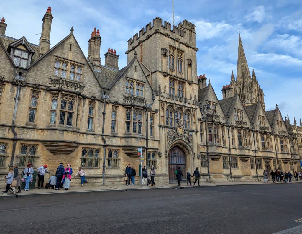 A view on a busy street in Oxford with University buildings and church.