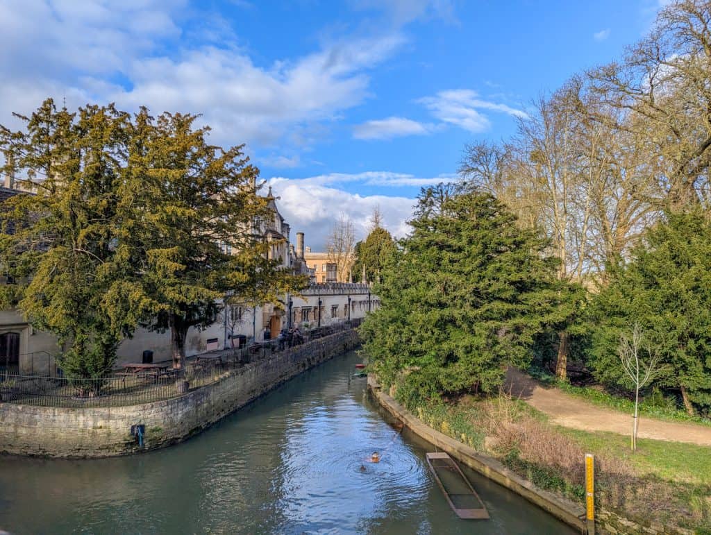 Quiet river with a punt and park in Oxford.