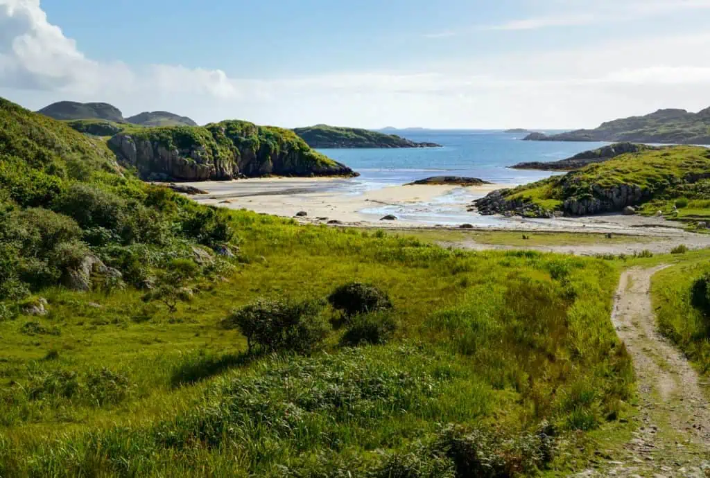 View at the Knockvologan Beach on Isle of Mull. Knockvologan Beach stretches along a peaceful bay near Iona, backed by rolling grassy hills.