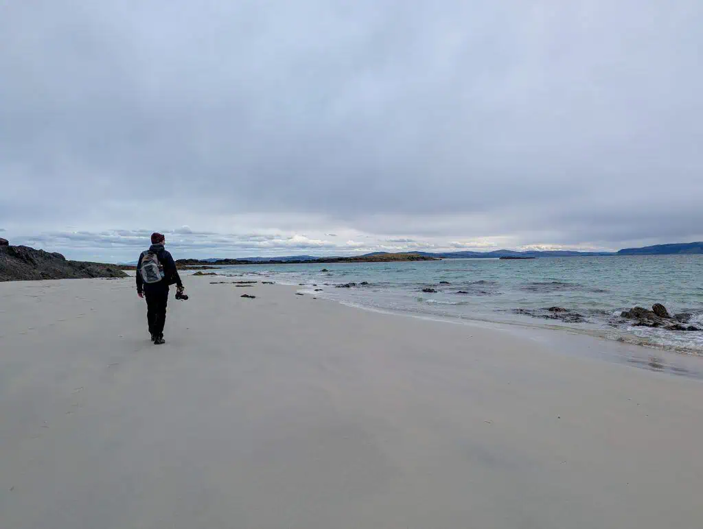 A person walking on a beach on Iona island.
