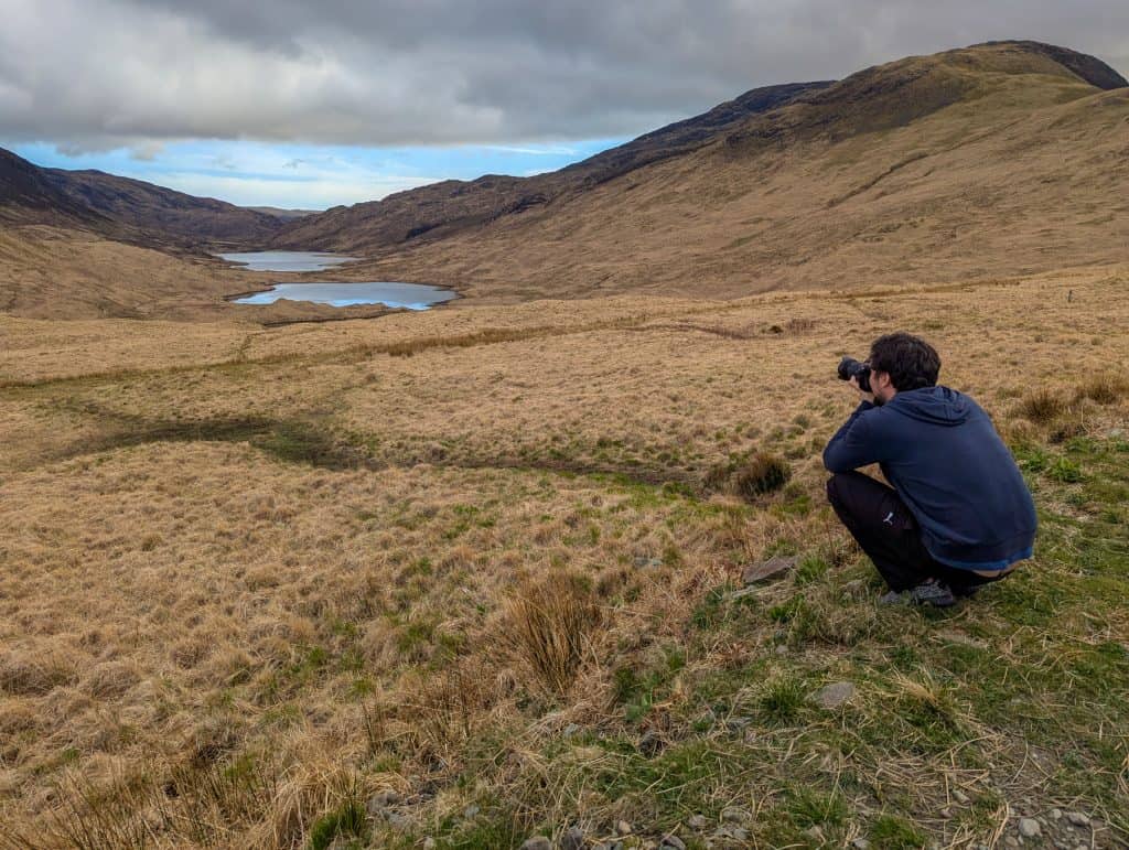 A photographer taking photos of the Three Lochs from a viewpoint.