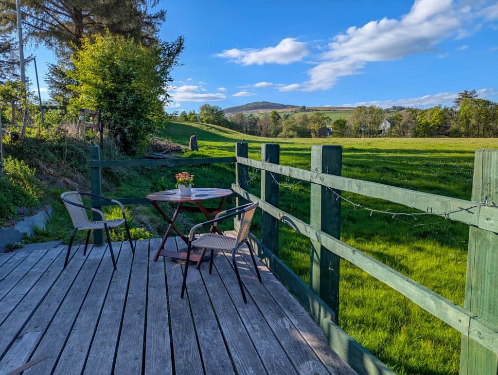 Views from accommodation in North Wales - patio with chairs and tables and views at a meadow.