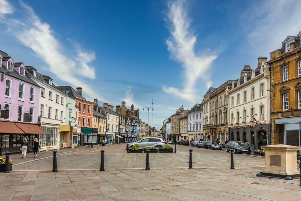 A main square in a city with historical houses and cars.