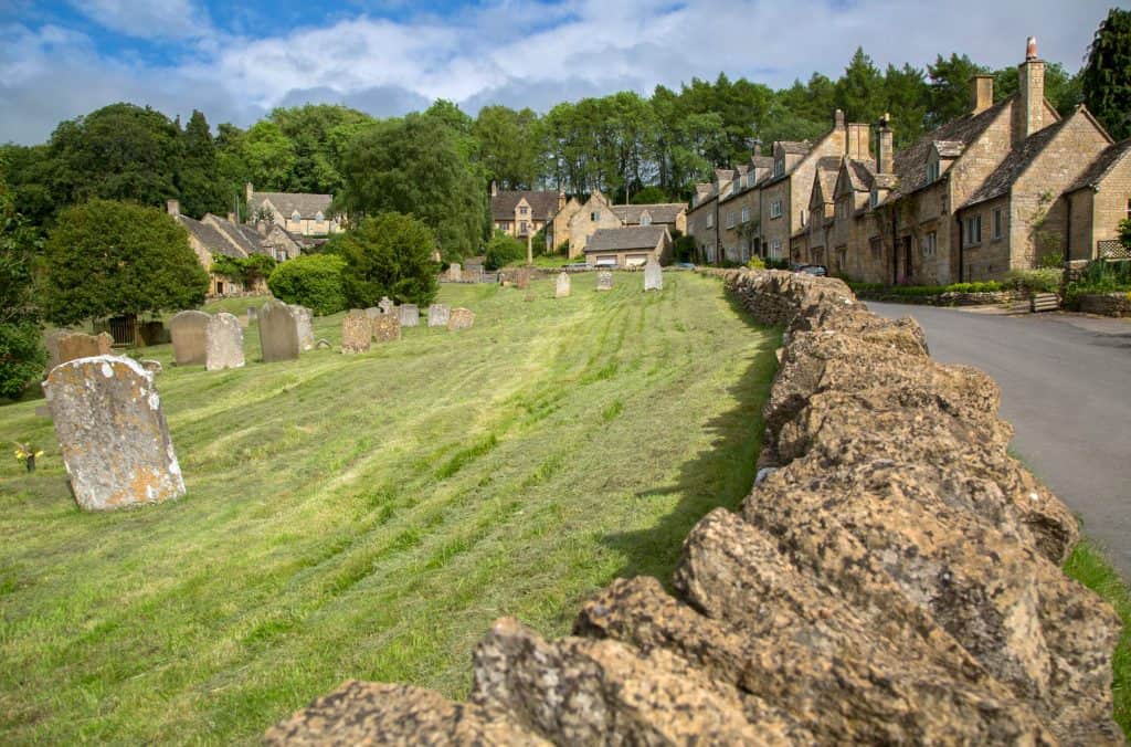 A street with historical mediaeval stone cottages and a grave on a sunny day.