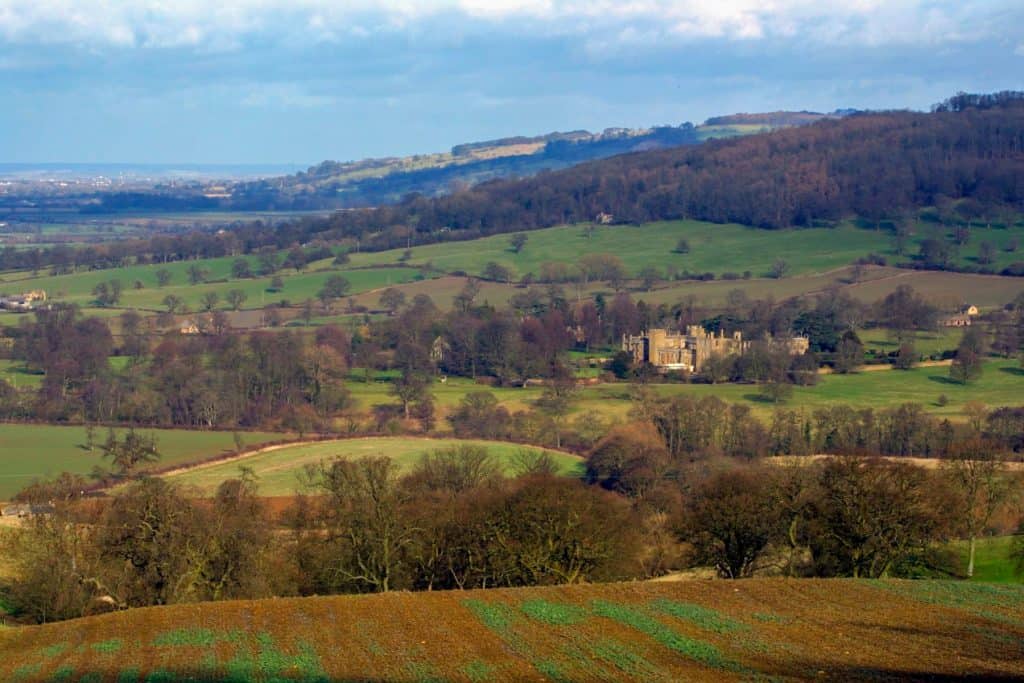 A view from a trail on a castle and woodlands in winter.
