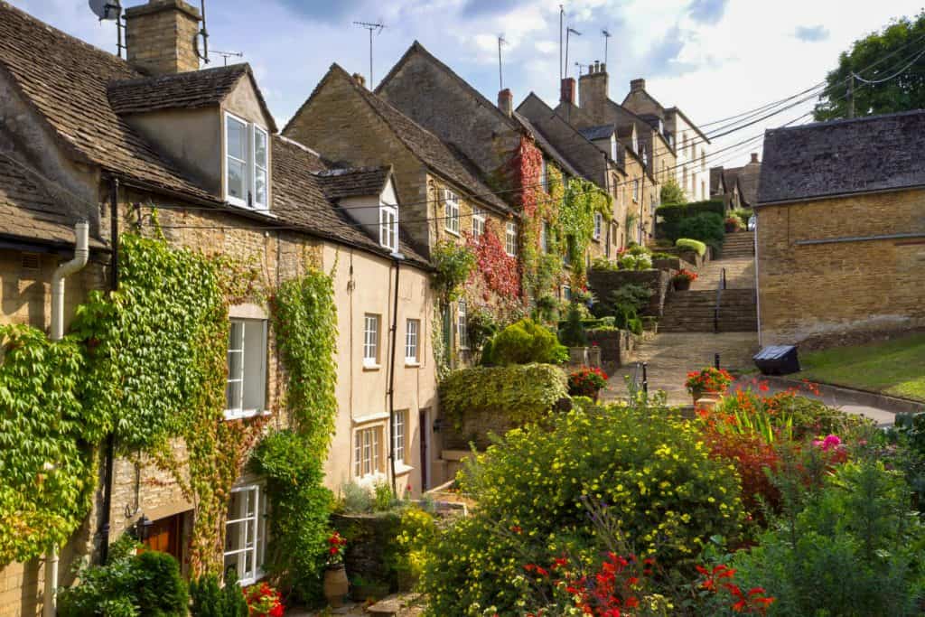 A hill street with historical mediaeval stone cottages on a sunny day.