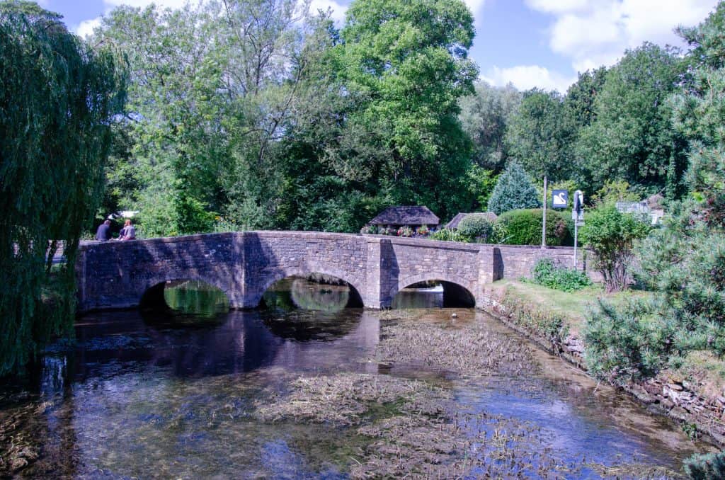 A view at a stone mediaeval bridge with river in Bibury in spring, one of the best villages in the Cotswolds.