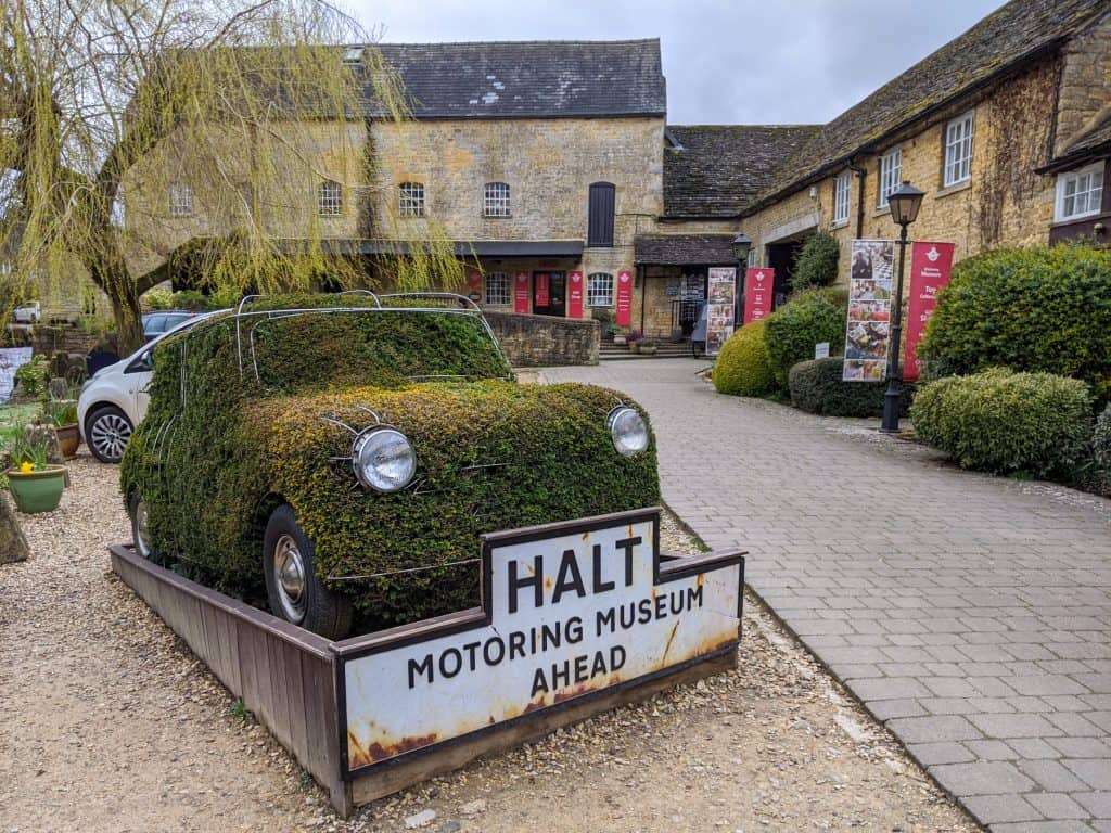 A view on a car covered in grass and old cottages in Bourton on Water.