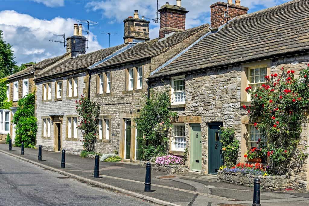 A street with a row of old cottages with roses.