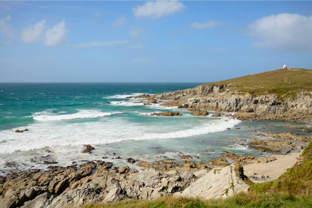 Views from a beach to the sea with cliffs at back.