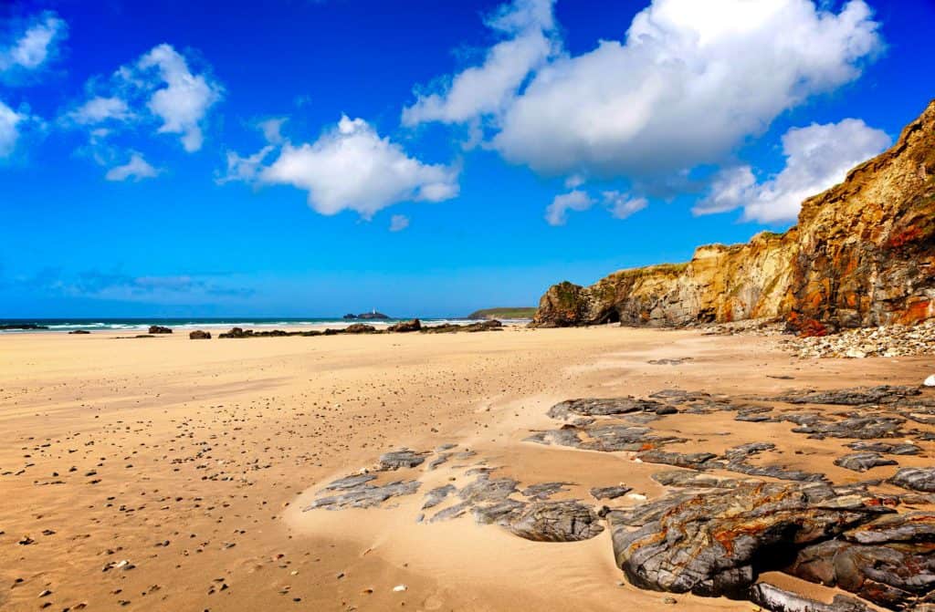 Sandy beach with cliffs and sea at back.