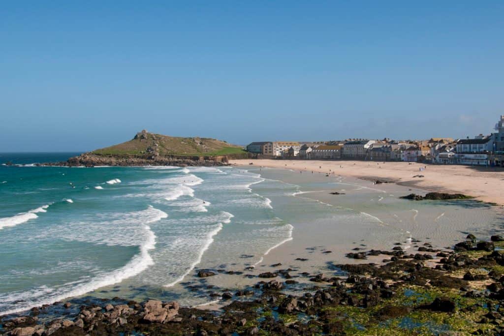 Long sandy beach with sea, cliffs and houses on the beach.