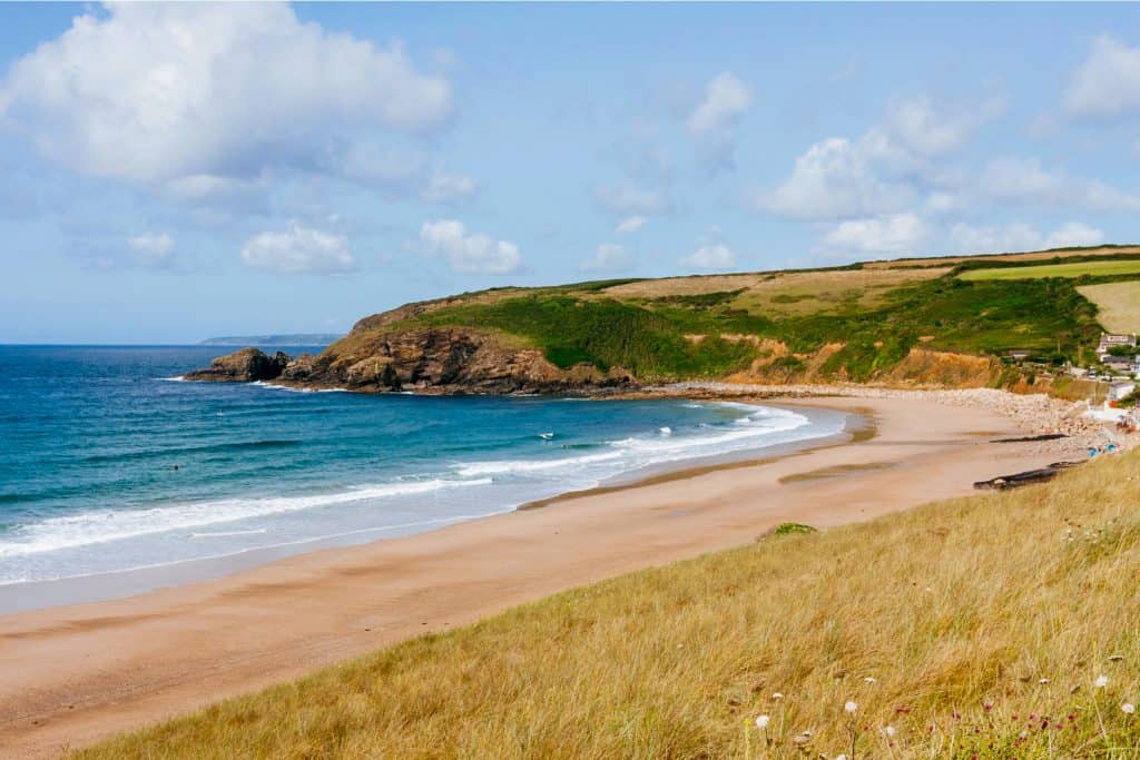Sandy beach with blue sea and cliffs.